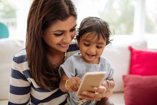 A mom and her toddler play with a smartphone