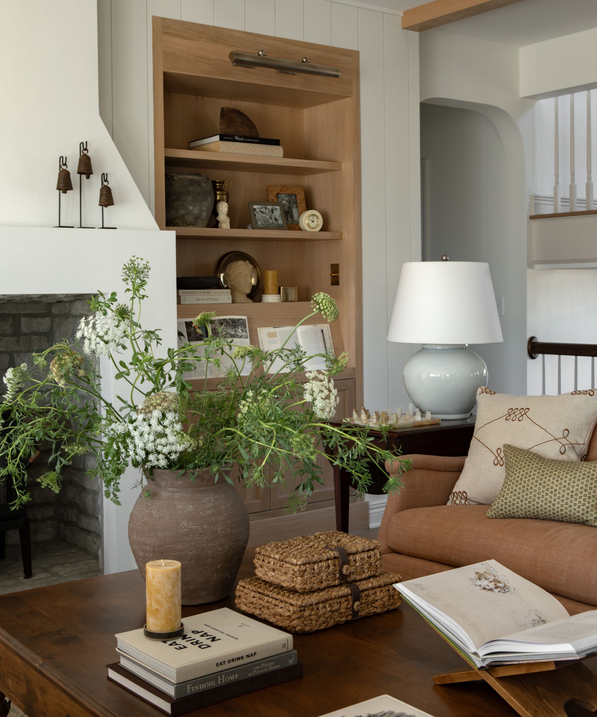 a neutral farmhous living room with oak bookcases with a plaster fireplace and wooden furniture