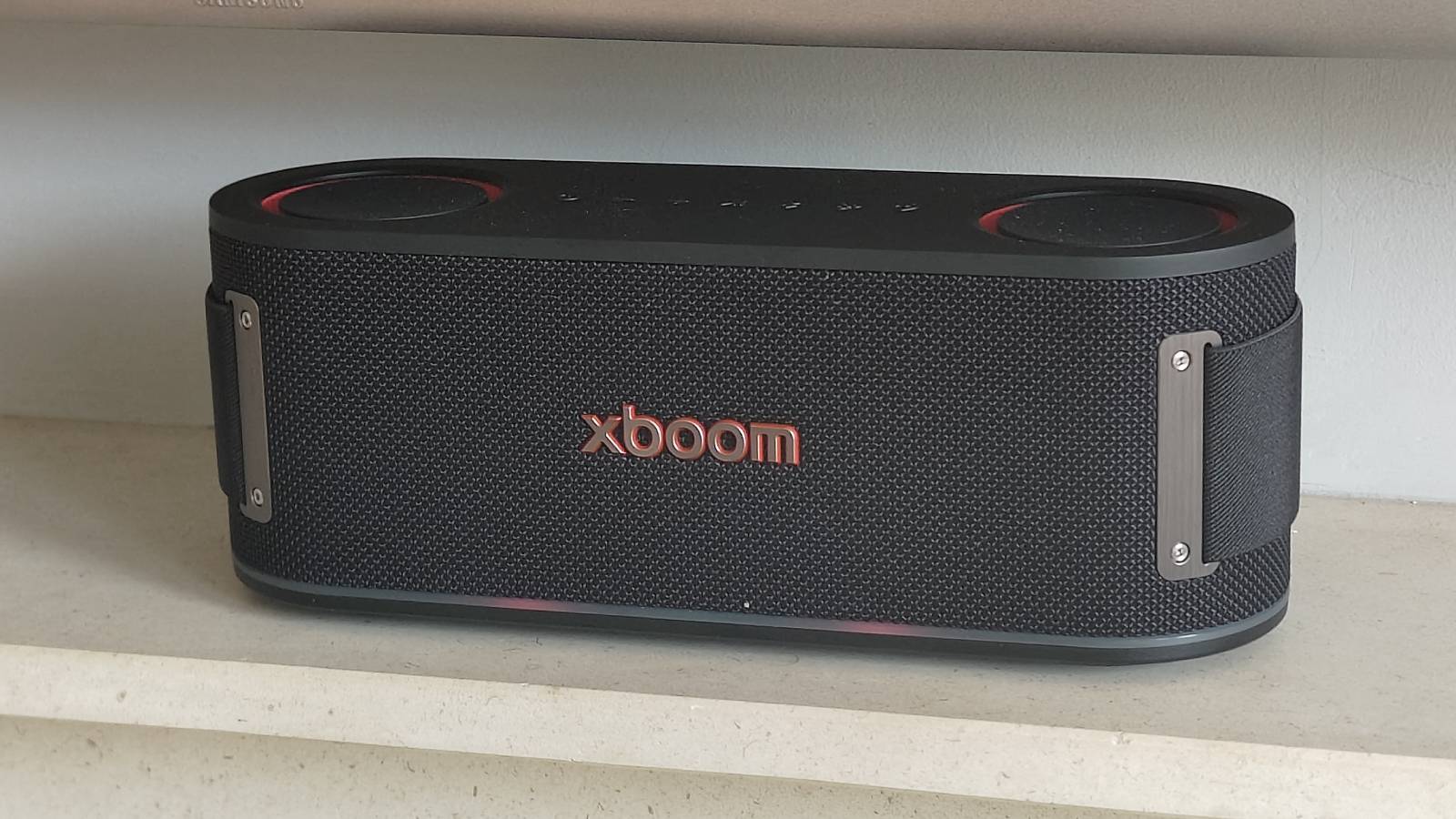 The LG xBoom Bounce by a leafy plant on a shelf.