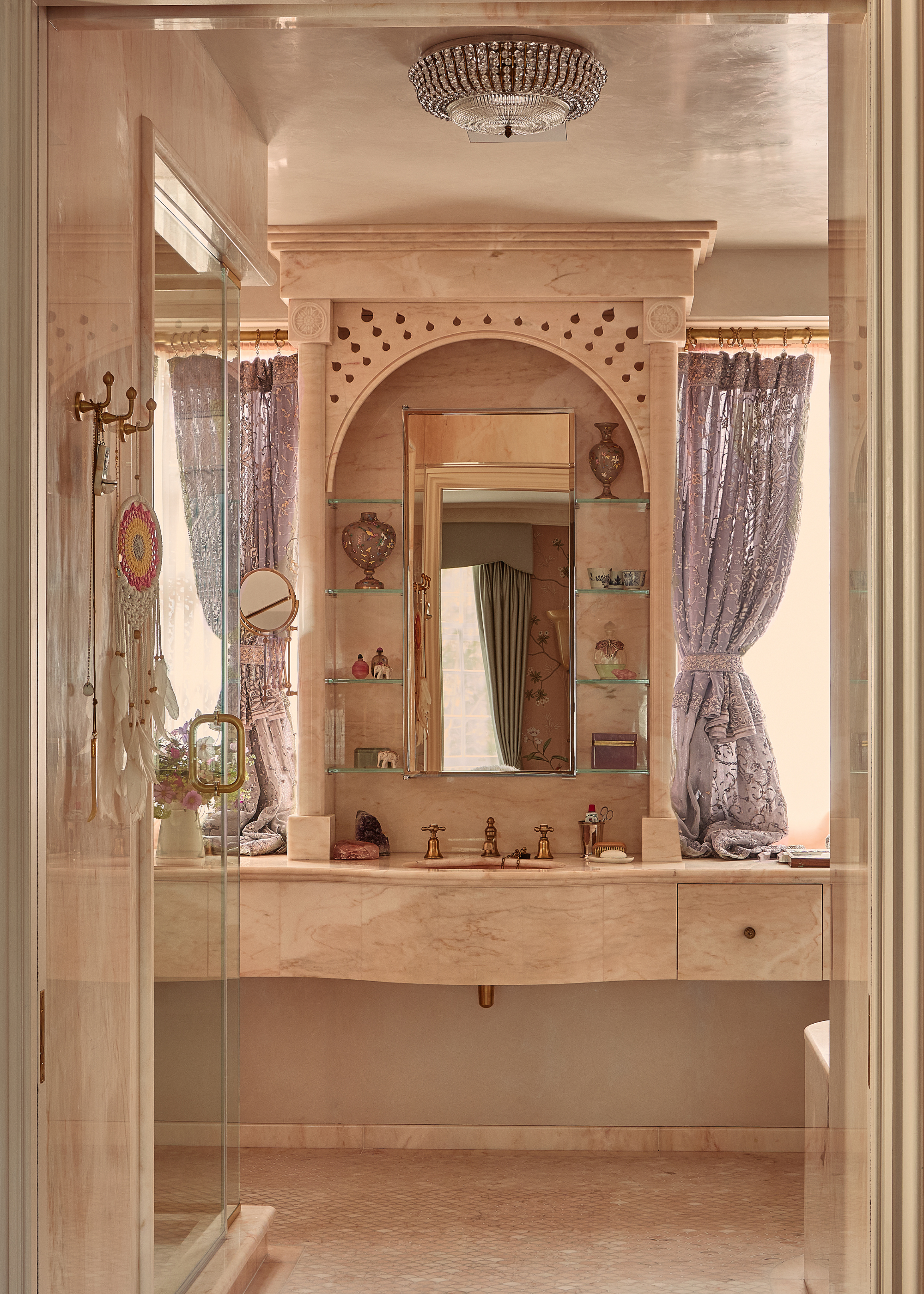 pink marble bathroom with a carved vanity and curtains on each side of the mirror