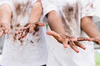 Two children wearing white t-shorts covered in mud