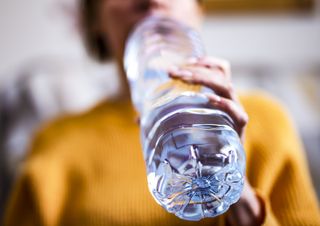 a woman drinking from a plastic bottle of water