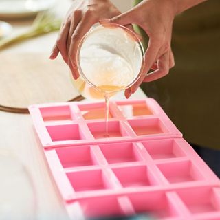 Close-up image of woman pouring melted soap with essential oils into plastic form alamy 2GE2MJG