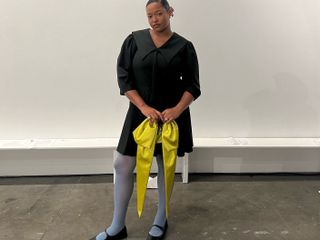 Woman wearing a black minidress with blue tights and a yellow handbag.