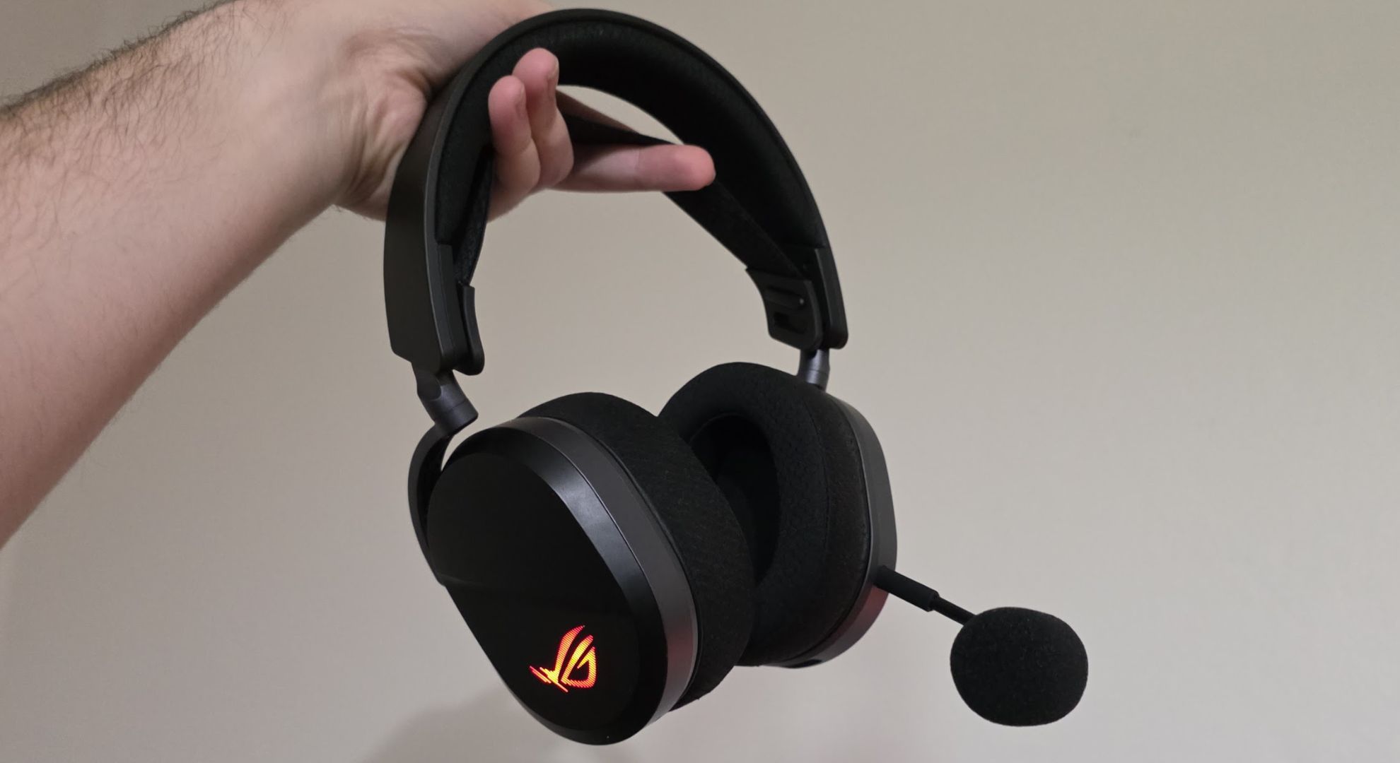 The Asus ROG Pelta gaming headset help by a hand, with the microphone inserted