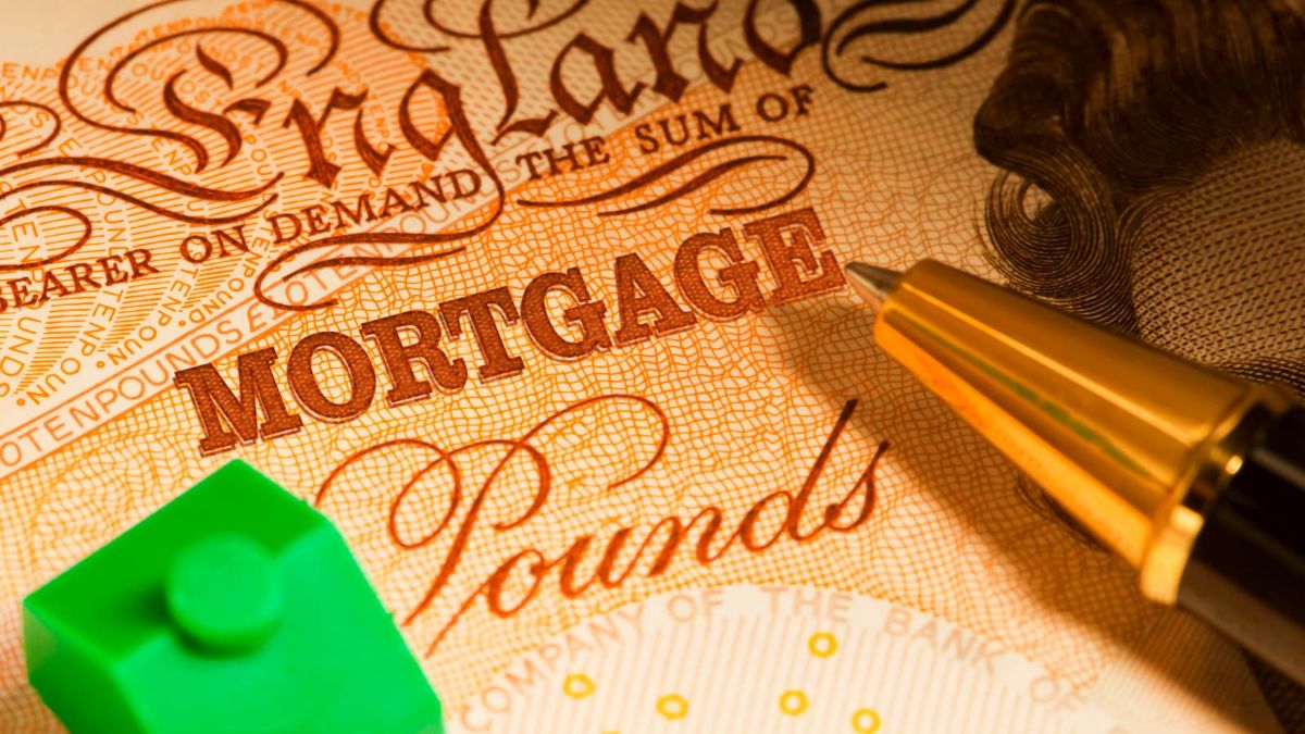 A UK Banknote for a Sterling Pounds Mortgage with a green toy house and a pen