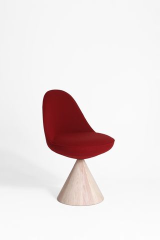 Red ‘Romby’ chair with wooden cone-shaped stand against a light coloured background