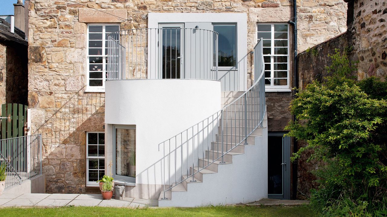 rock exterior home with staircase and potted plant 