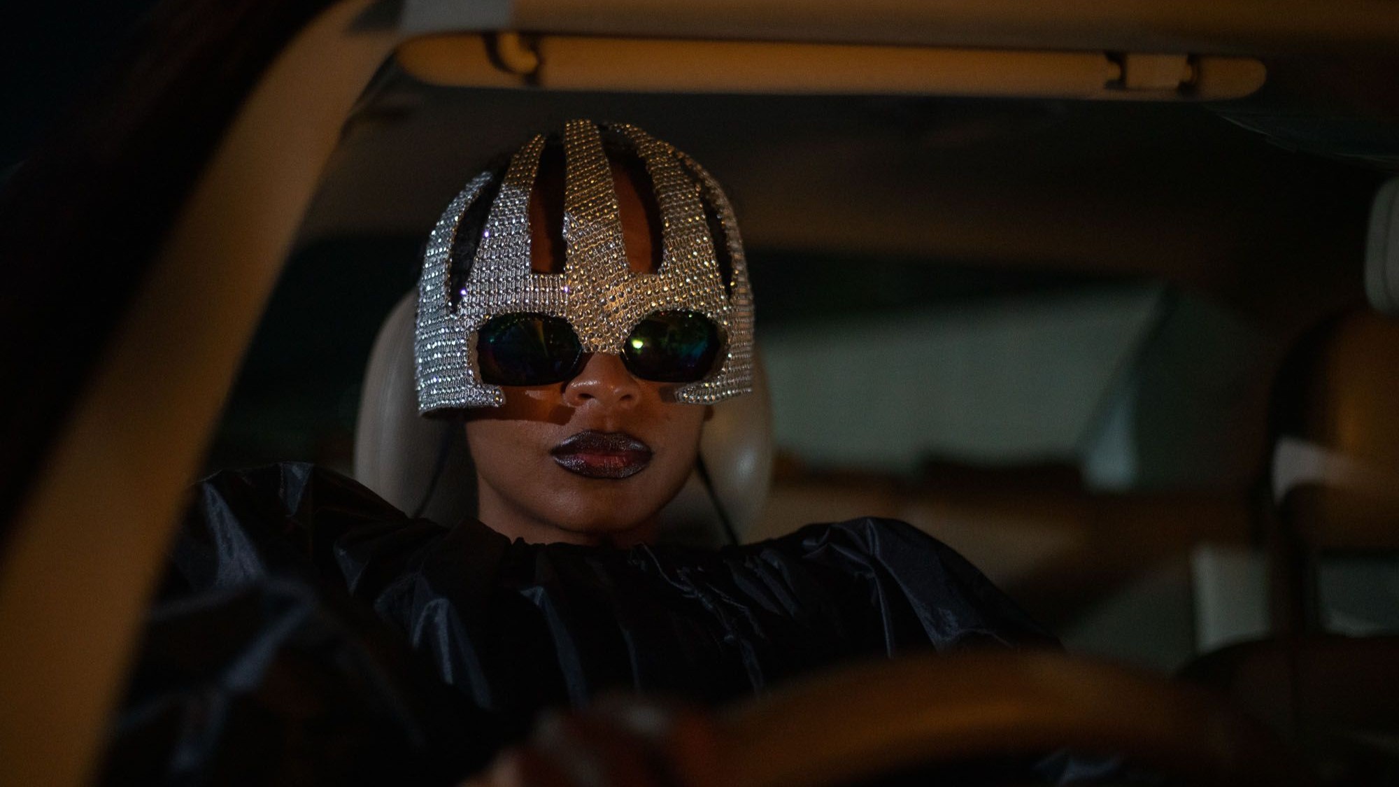 Susan Chardy driving a car in bedazzled sunglasses in On Becoming a Guinea Fowl