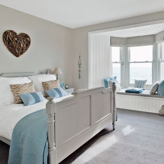 bedroom with grey wall grey floor white window and grey bed with designed cushions
