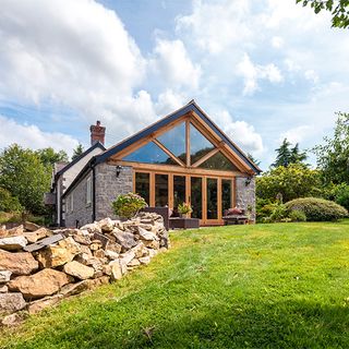 house exterior with stone wall wooden and glass door with garden