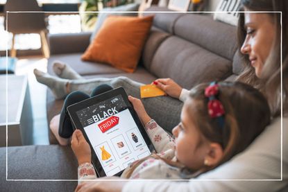 Mother and daughter sitting together on the sofa while looking at Black Friday sales on an iPad