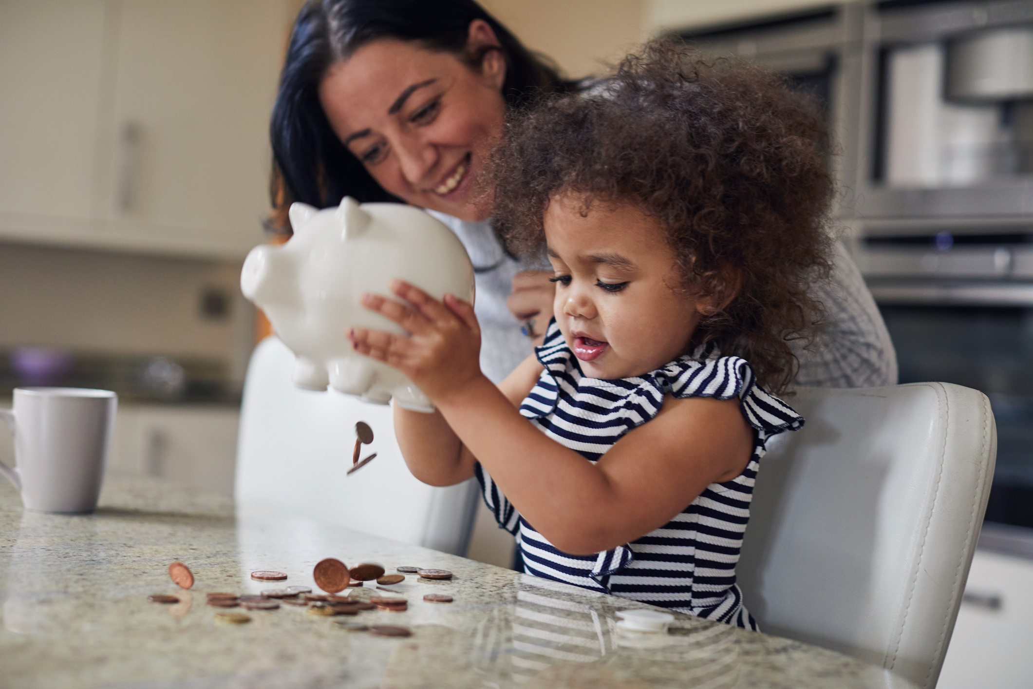 Child and parent looking at savings in a piggy bank