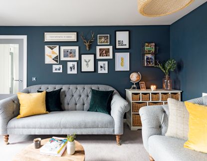 house renovation with a dark navy living room with yellow accents and a grey sofa