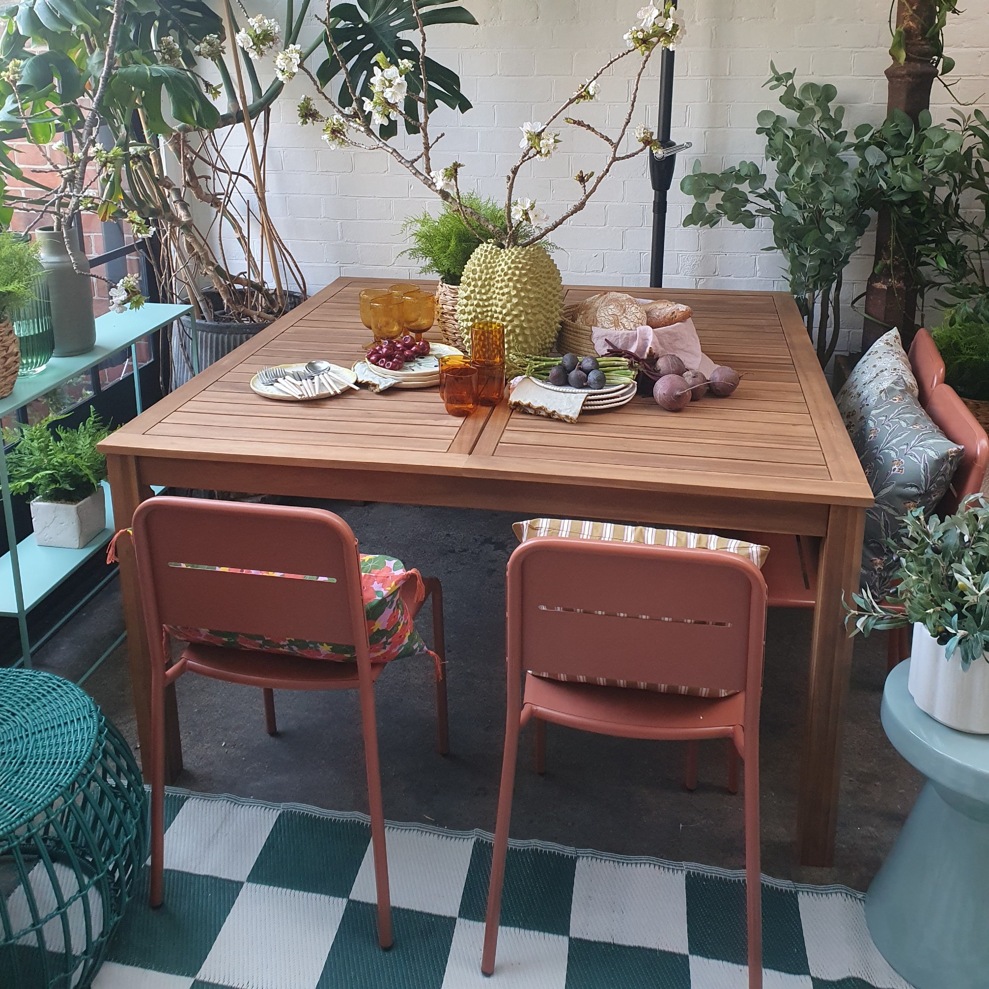 A wooden outdoor dining table and a set of terracotta-shade aluminium garden chairs at the La Redoute spring/summer 2025 press preview