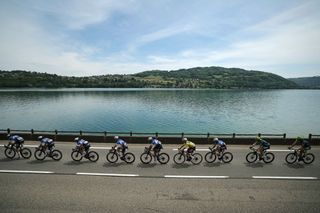 Team Soudal's Belgian rider Remco Evenepoel wearing the overall leader's yellow jersey (4thR)) rides in the pack by Paladru's lake during the sixth stage of the 76th edition of the Criterium du Dauphine cycling race, 174,1km between Hauterives and Le Collet d'Allevard,f French Alps, on June 7, 2024. (Photo by Thomas SAMSON / AFP)