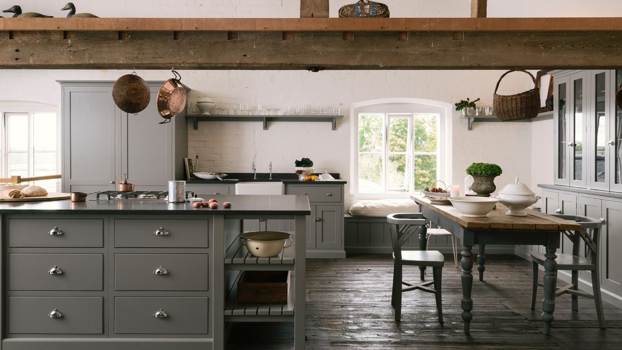 Gray kitchen with beams, wooden floor, black countertops, hanging copper pans, open shelving, storage ideas, farmhouse style,