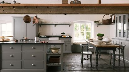 Gray kitchen with beams, wooden floor, black countertops, hanging copper pans, open shelving, storage ideas, farmhouse style,