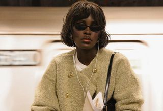 Woman wearing a J.Crew jacket and oval sunglasses.