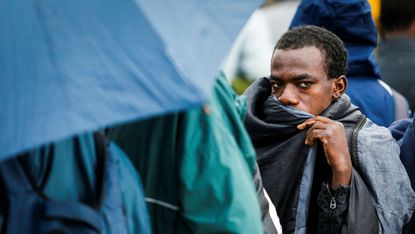 Migrants queue to enter the refugee centre near Porte de la Chapelle, northern Paris