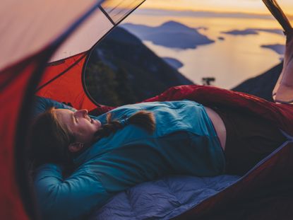 best camping bed: pictured here, a hiker laying in a a one-person tent