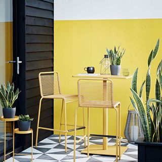 outdoor wall with yellow and white paint and yellow table and stools