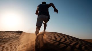 A man running on a sand dune in the desert