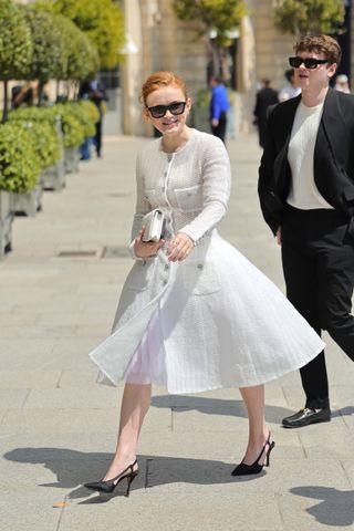 Sadie Sink wears a white Chanel dress with a voluminous skirt and black slingback heels.
