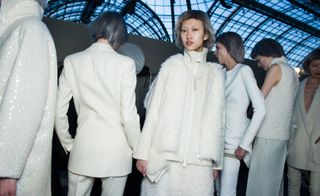 Models backstage, dressed in variations of white outfits