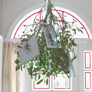 A bright white hallway with an arched doorway decorated with a mistletoe hanging from the ceiling for Christmas