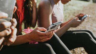 Three woman holding their mobile phones outside and looking at the screens - stock photo
