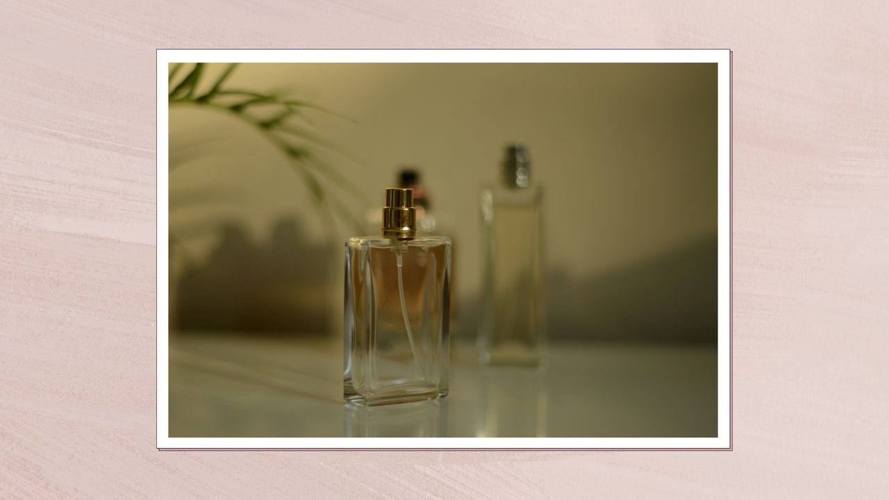 Three glass perfume bottles are pictured on white shelf, in front of a shadowed background and in a pink template