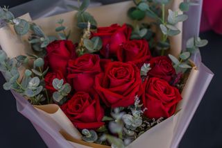 A close up of a bouquet of red roses with sprigs of eucalyptus.