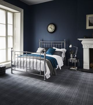 dark blue scheme bedroom with large metal finish bed and checked carpet