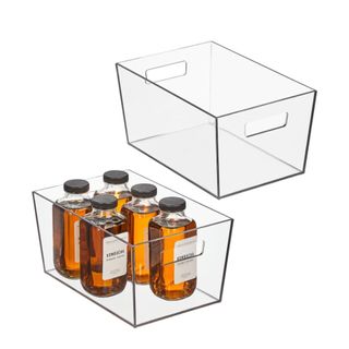 Two rectangular plastic bins with handles at an angle, with the lefthand bin containing five glass bottles with brown liquid and black caps