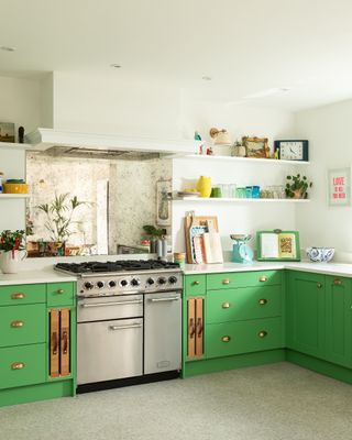 green kitchen with white walls and counterop, stainless steel range, open plan shelving, vintage mirror backsplash