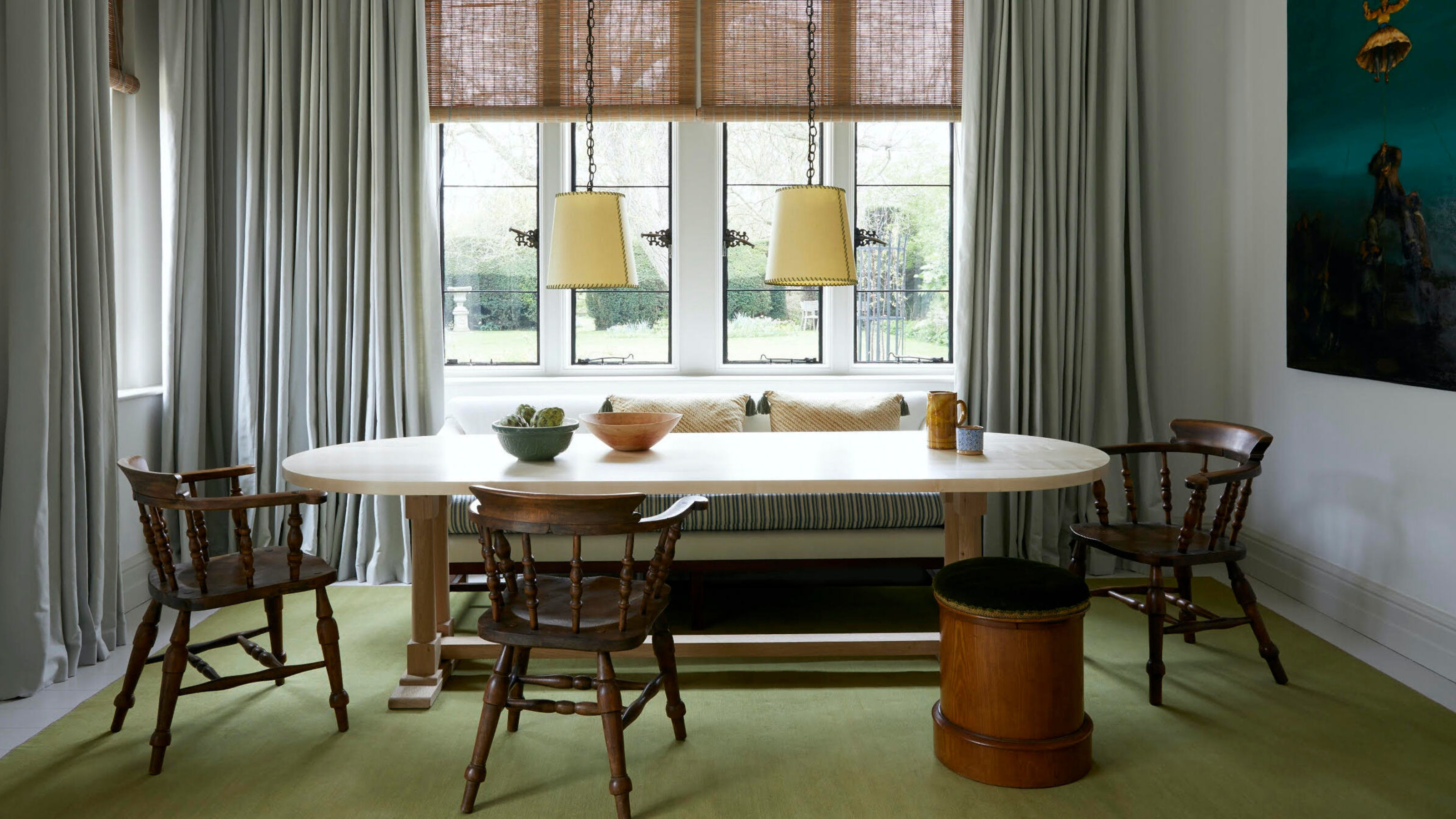 banquette seating in a window bay with oval dining table and timber chairs