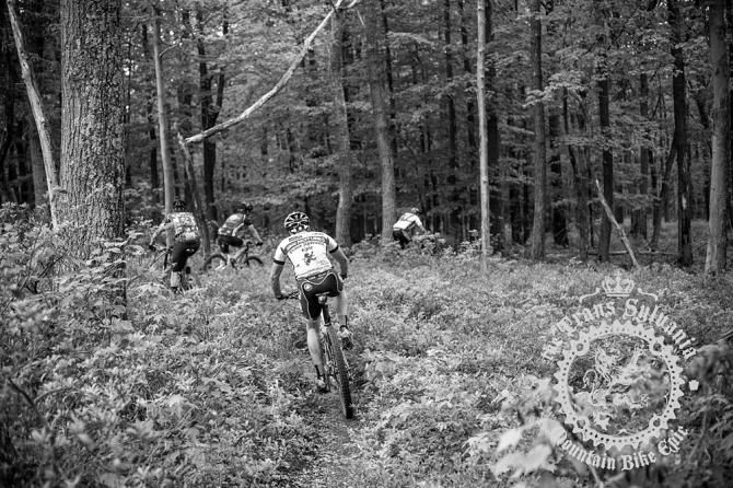 Riders racing through a corner in the woods.