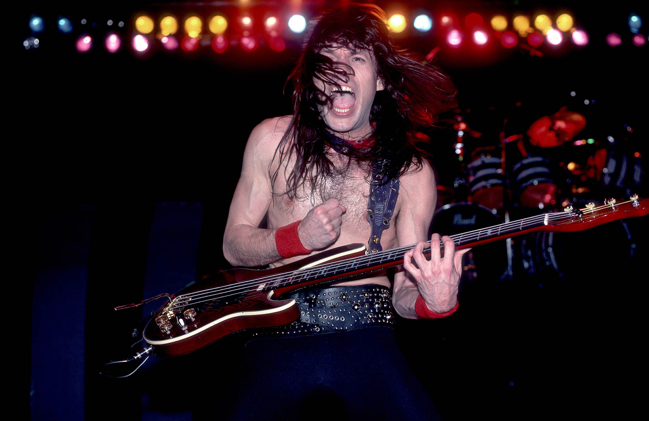 Rudy Sarzo, shirtless, screaming, plays his bass with Quiet Riot in 1984, returning to the band after a successful stint with Ozzy Osbourne.