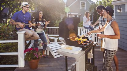 friends standing around a grill on a deck
