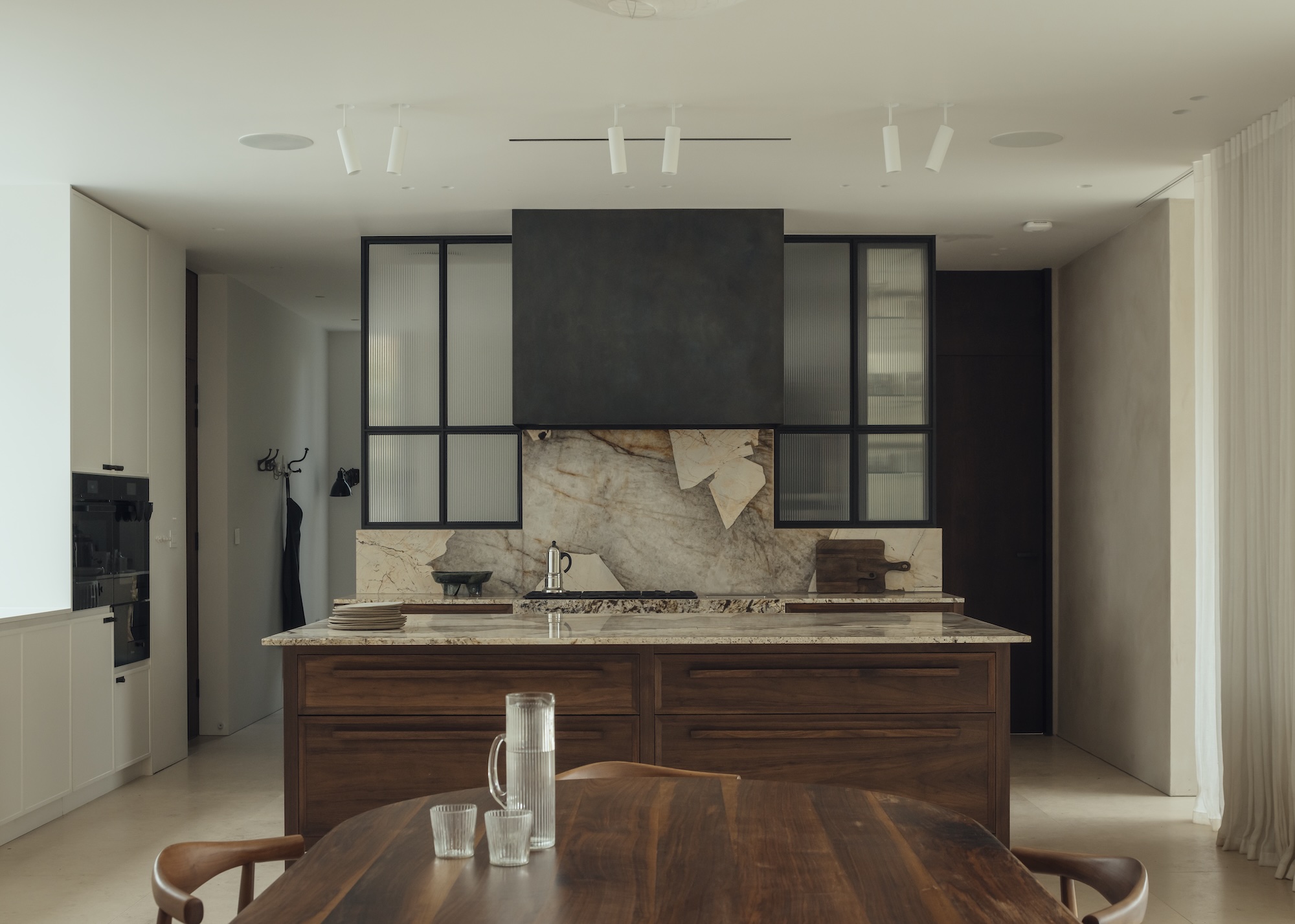 a dark wood kitchen with a limestone worktop and backsplash and accents of dark wall cabinets