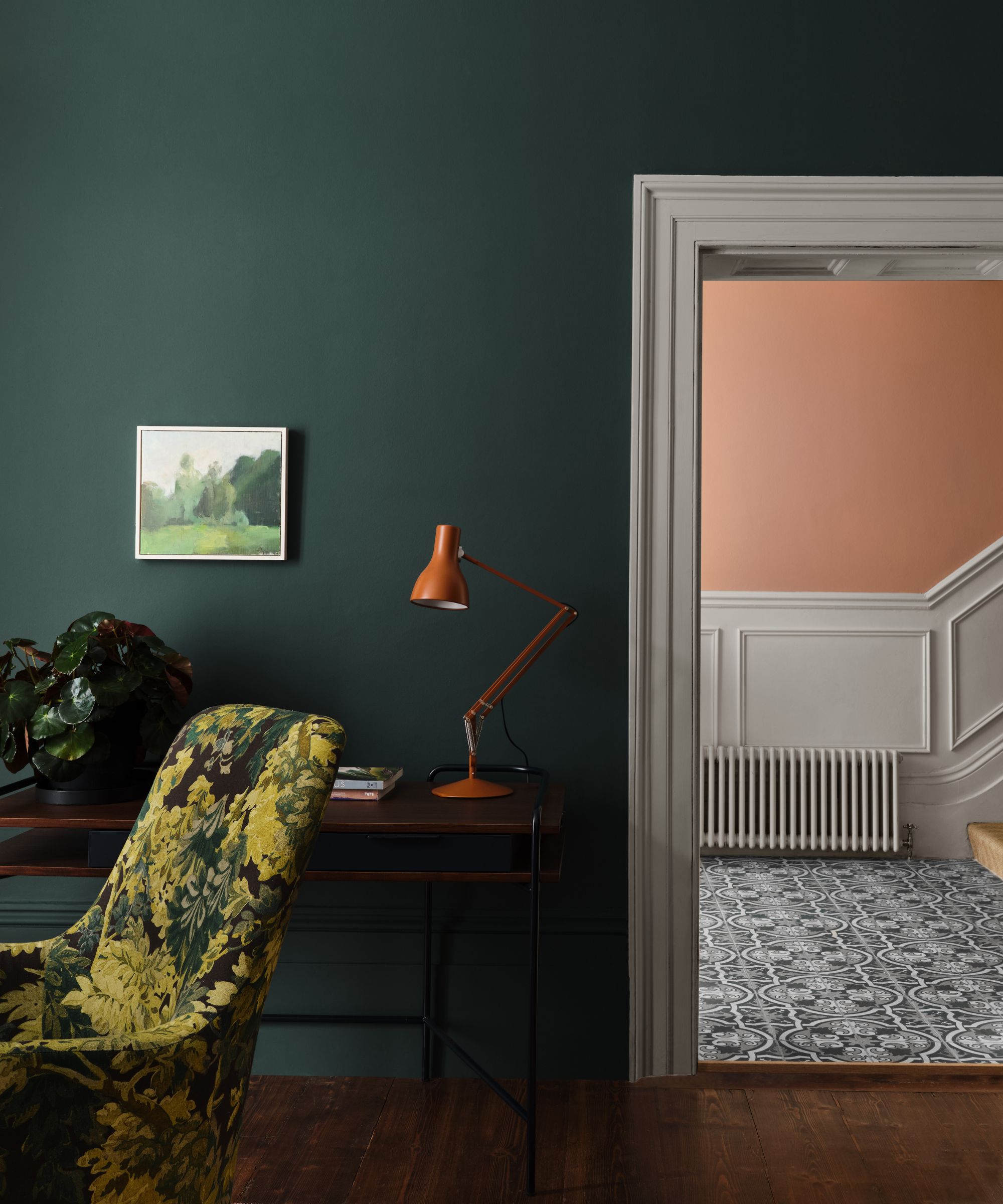 A living room with dark teal walls and a peach hallway.