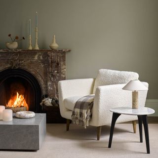 Cream boucle armchair in living room with fireplace and coffee table