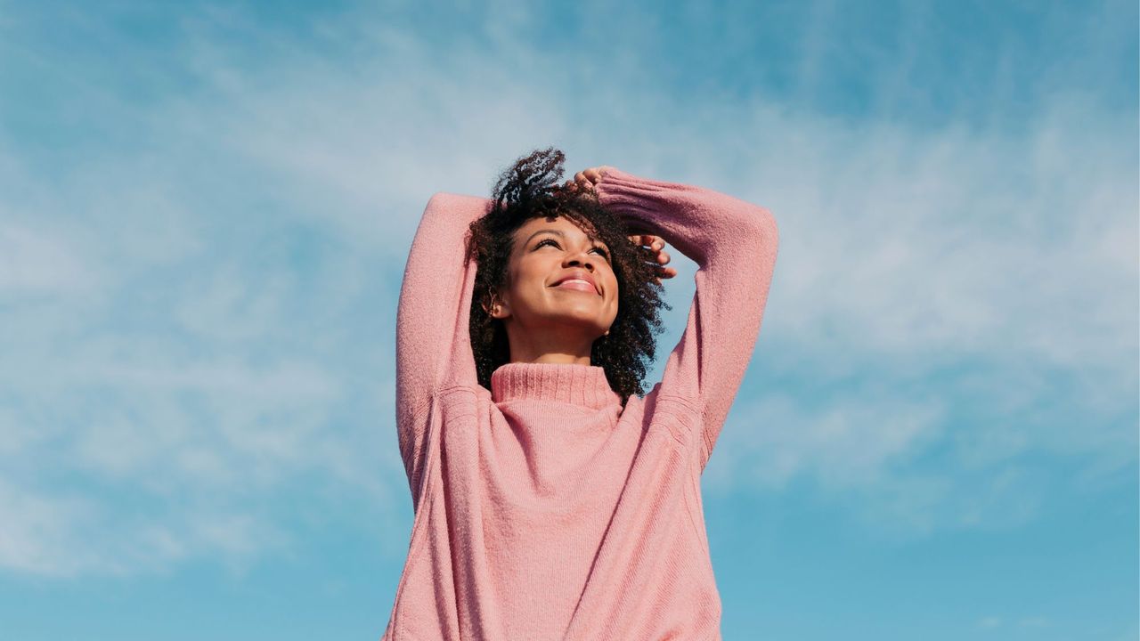 How to avoid a cold: A woman outside with her arms in the air