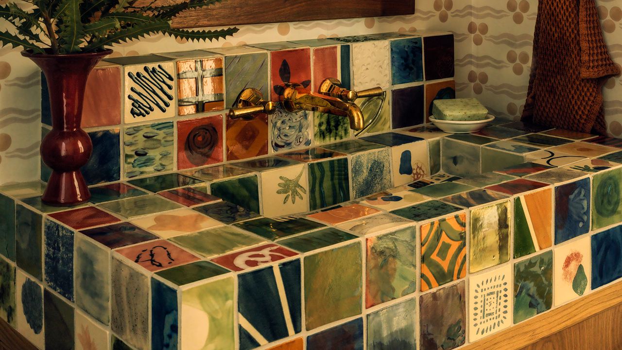 a full painted tiled sink in a wallpapered bathroom