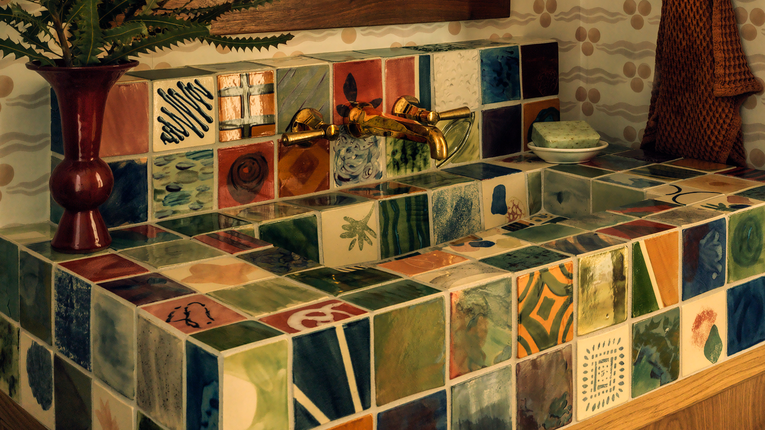 a full painted tiled sink in a wallpapered bathroom