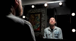 In this backstage shot, singer-songwriter Seb Wesson wears a worn denim jacket and stares into the mirror lined with lightbulbs.