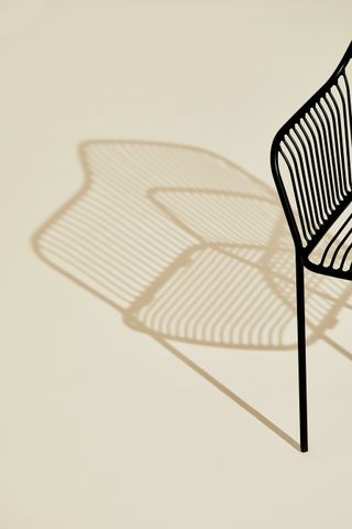 The black garden chair by Benjamin Hubert for Allermuir in black. The chair's shadow references the lines of crops in the British countryside