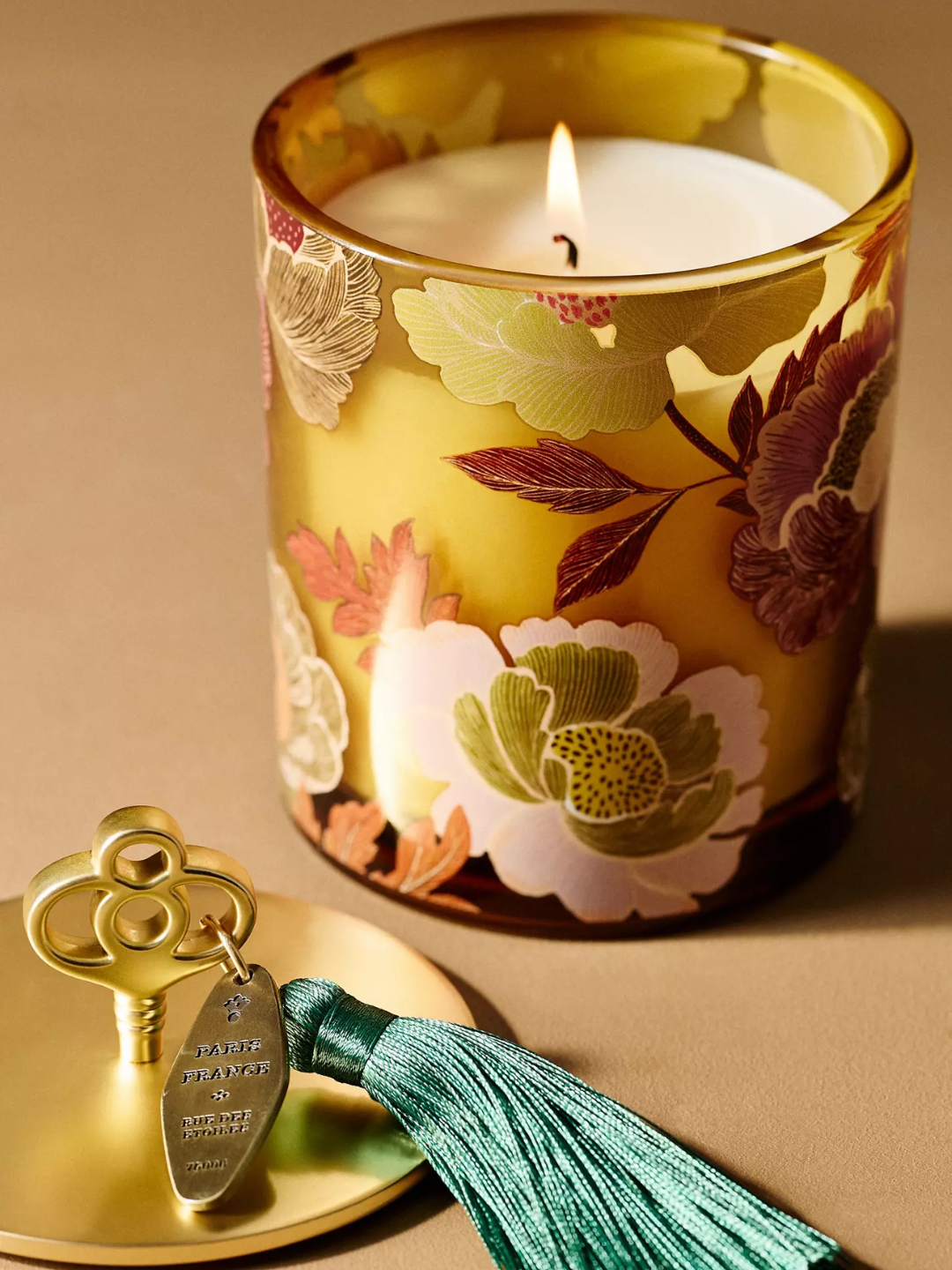 A glass honeycrisp oakwood candle with a floral facade and a brass lid