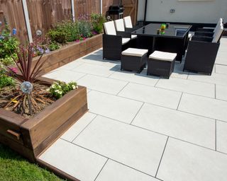 Clean white slab patio in backyard with furniture and plants, shot from high angle